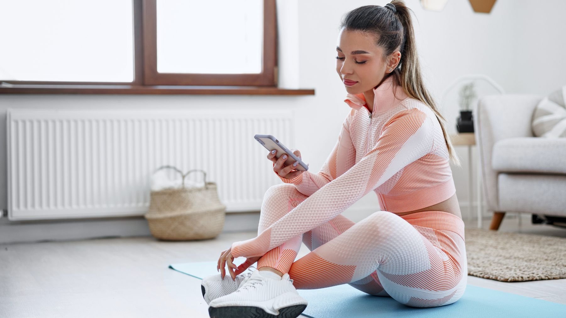 Woman in sportswear with smartphone indoors