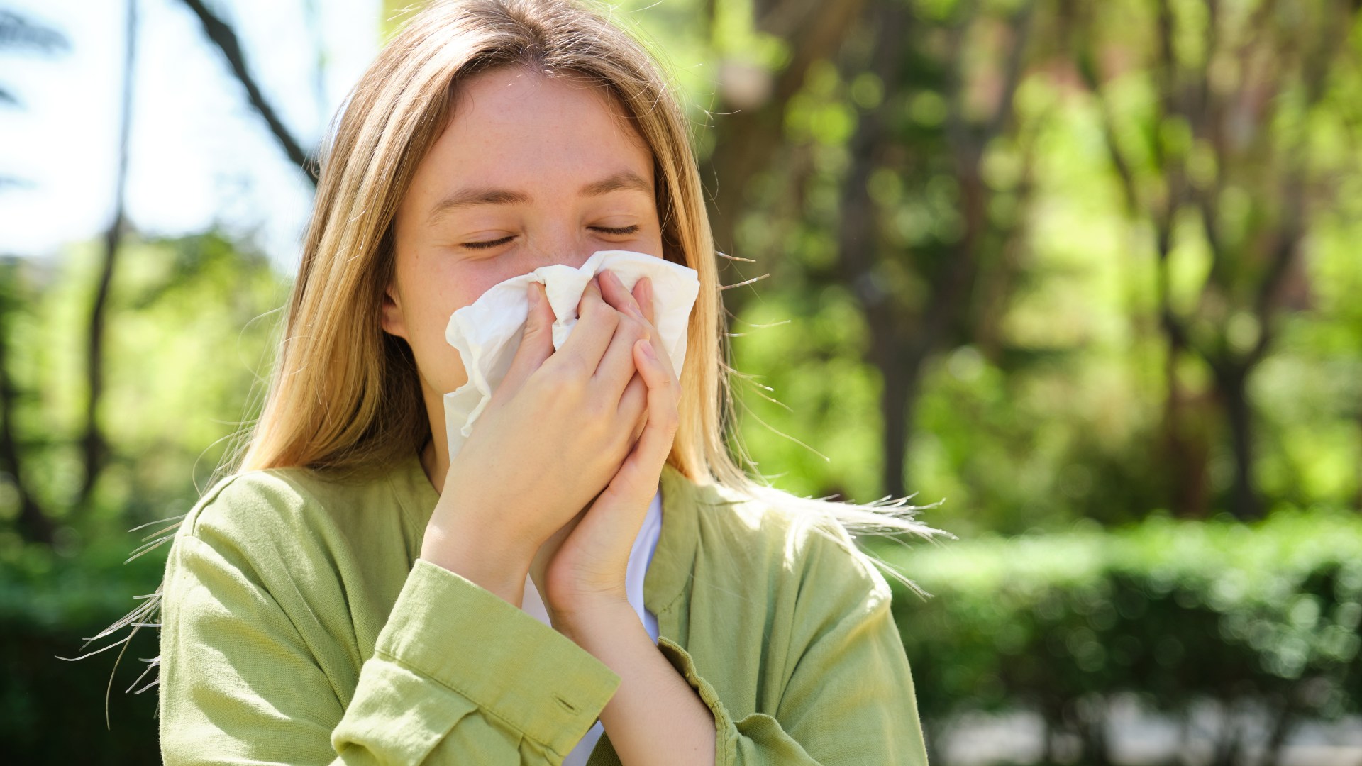 blonde woman blowing nose tissue 1003775045