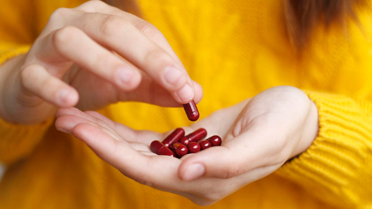 person holding red vitamins in hand