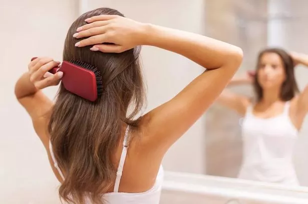 2 Young woman brushing healthy hair in front of a mirror