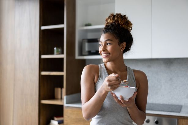 0 Happy woman at home eating a bowl of cereal for breakfast