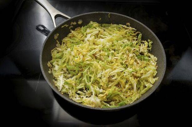 0 Savoy cabbage in a frying pan on the black stove cooking at home with healthy winter vegetables selected focus narrow