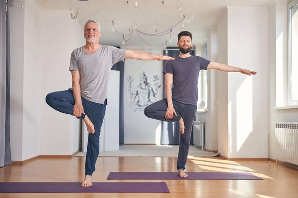 0 This is a photo a young man and an old man both balancing on one leg on yoga mats See PA Feature HEALTH Strength