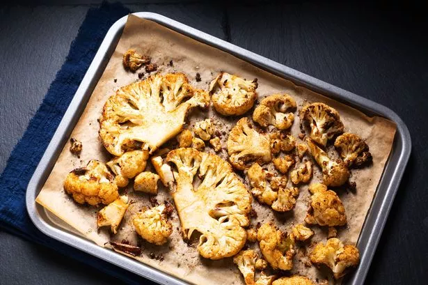 1 Food concept Roasted organic Cauliflower in baking tray on black slate stone background with copy space