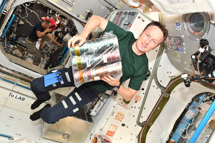 Microgravity meals: Tackling taste, texture & safety challenges in space food - foodingredientsfirst.com 4 638981072427963884male astronaut in tshirt and pants inside ISS holding a pack of food cans