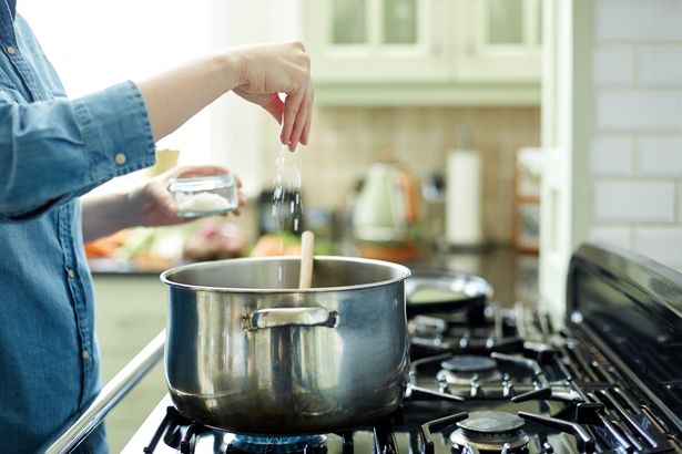 Home cooking one meal a week could lower your risk of dementia in later life 1 0 Woman adding salt to cooking pot on stove