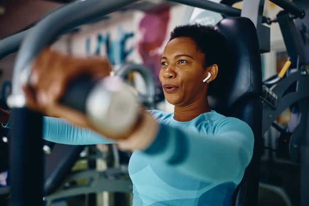1 Black sportswoman doing chest exercises on machine while working out in gym