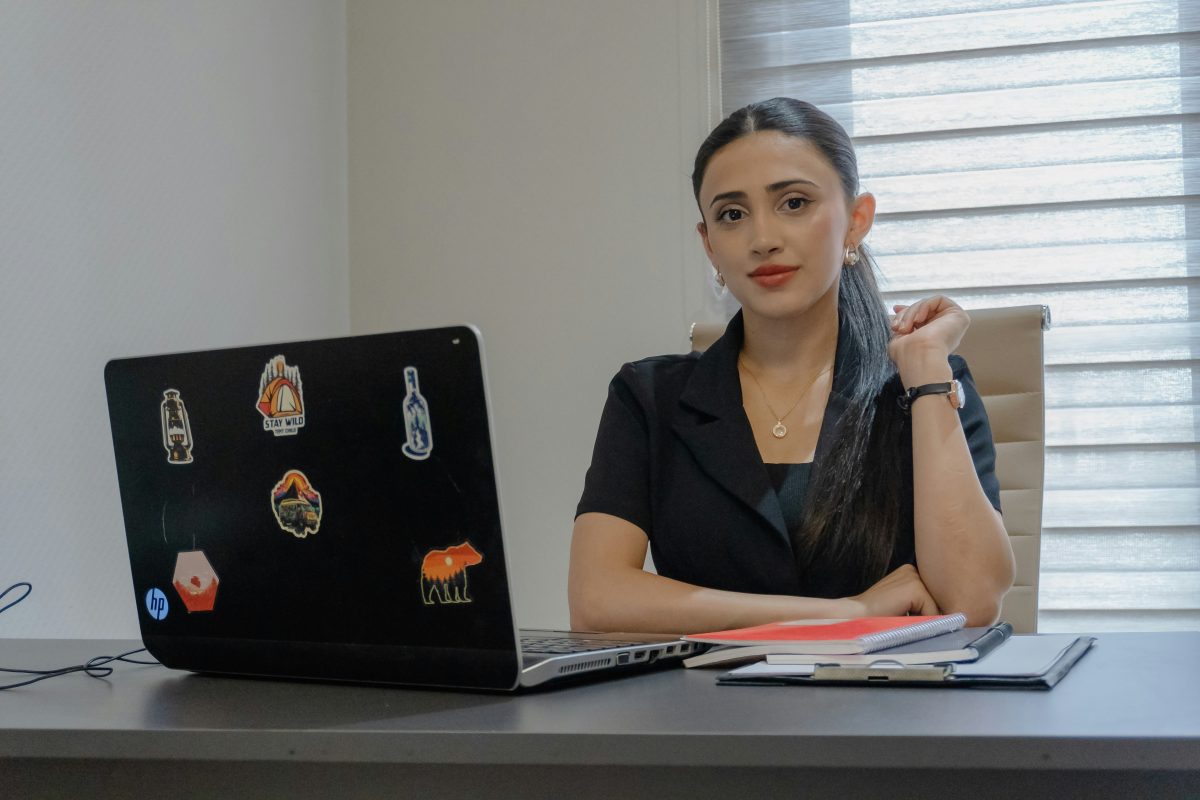a woman sits at a desk with a laptop
