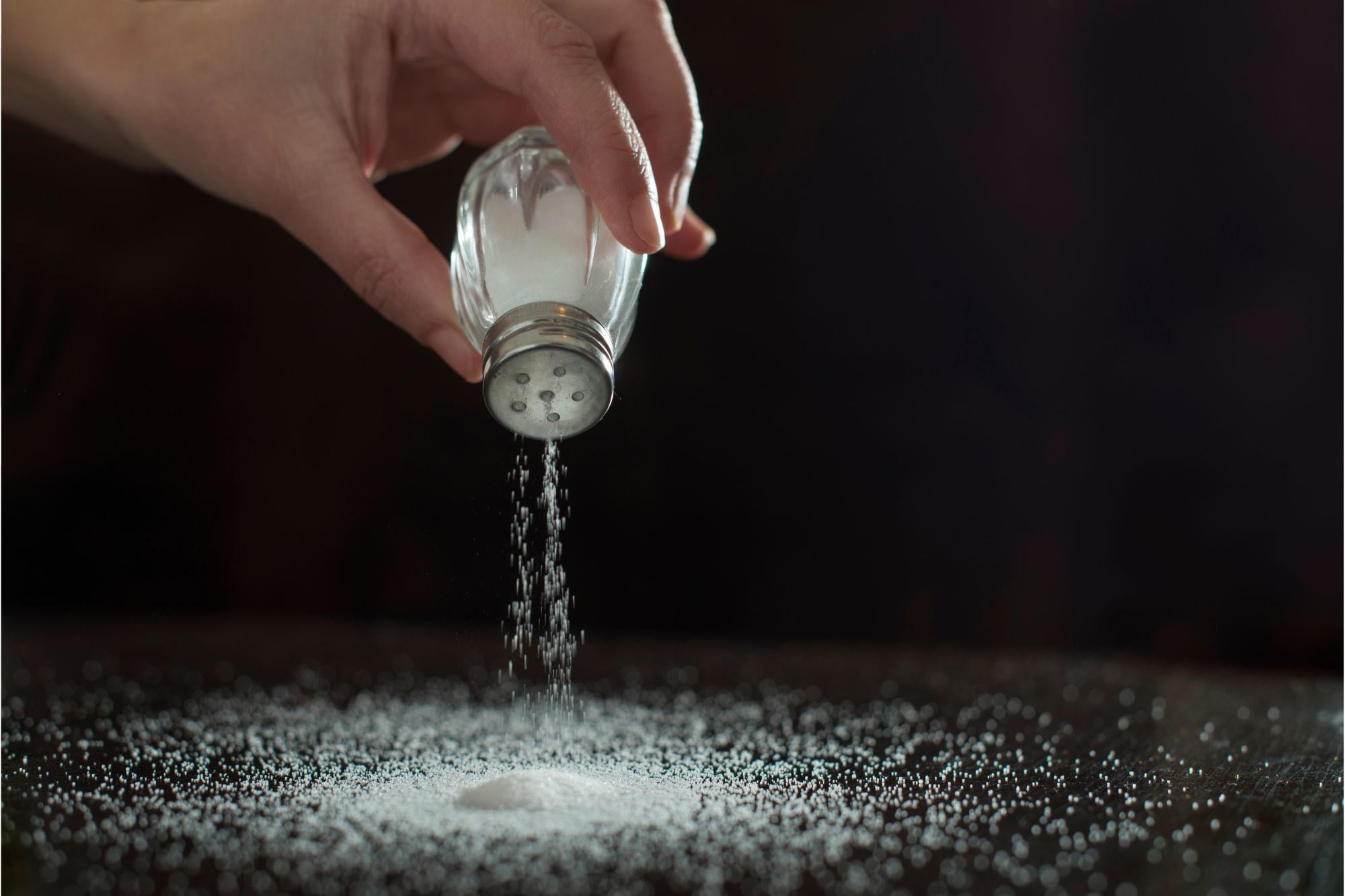 Are You Adding Too Much Salt? New Study Identifies Whos Most at Risk - SciTechDaily 2 Sprinkling Salt on Table Concept