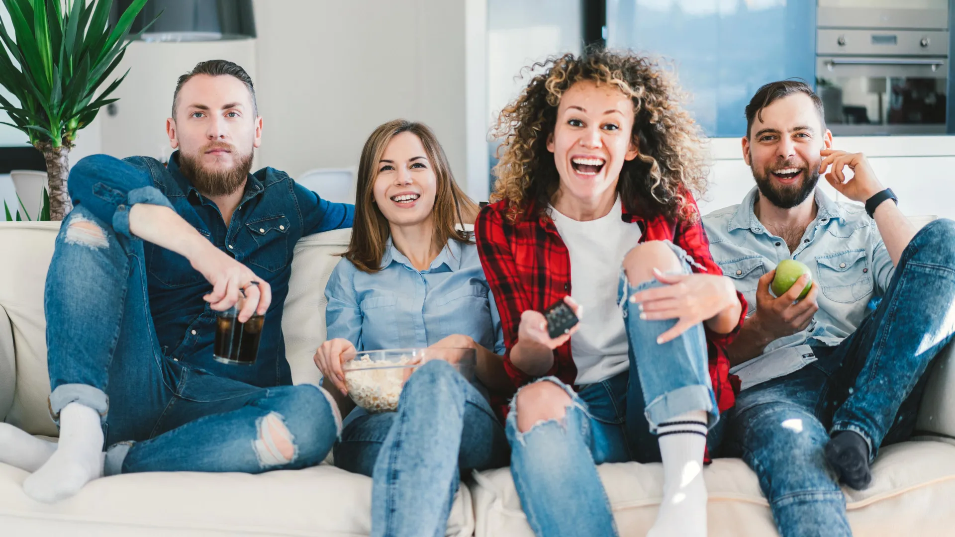 young people friends watch tv on sofa in living room