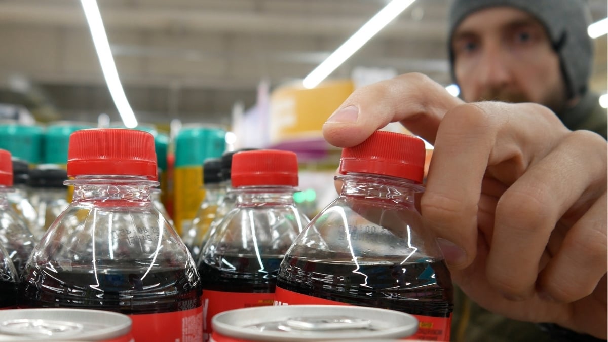 A buyer takes one plastic bottle of cola in a supermarket close up
