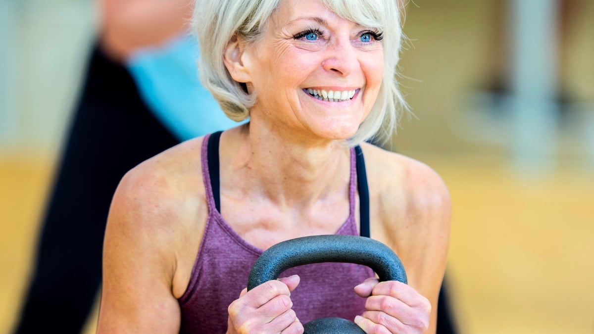 Happy Older Woman Exercising LIfting Kettlebell