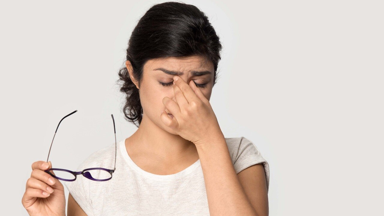 tired indian girl taking off glasses massing nose bridge isolated on grey studio background exhaus 025349900 original sixteen to nine