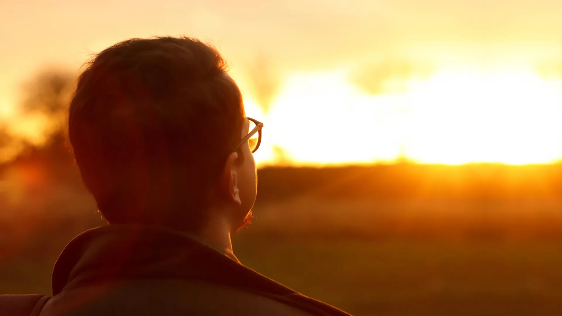 man looking at bright rising sun